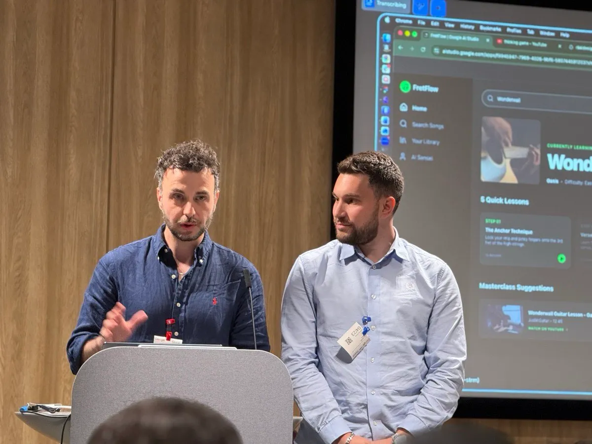 Two members presenting FretFlow, a guitar-learning app built in Google AI Studio, projected behind them with a Wonderwall lesson open