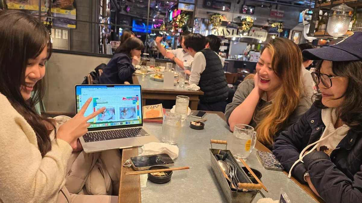 Four of us around an izakaya table after a session, one turning her laptop around to show a design board